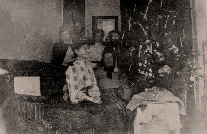 Олександр Грушевський (стоїть перший праворуч) з дружиною Ольгою (стоїть по центру) та невідомі біля ялинки. Київ, Паньківська, 9. 1920-ті рр.